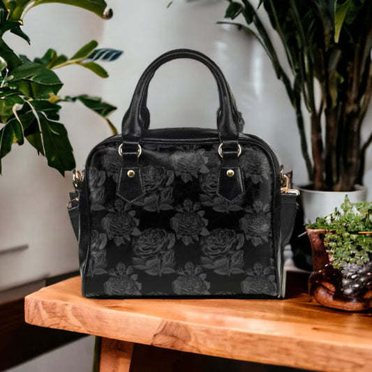 Black floral patterned handbag on a wooden table with plants in the background